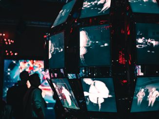 a group of people standing around a display of video screens