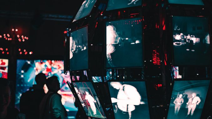 Photo by Maxim Hopman a group of people standing around a display of video screens